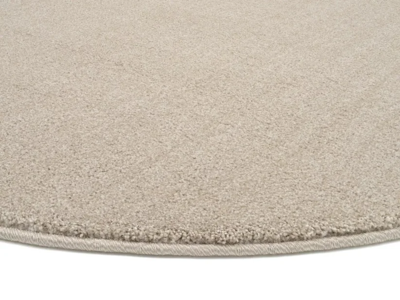 Béžový kruhový koberec je elegantne obšitý vo farbe koberca.