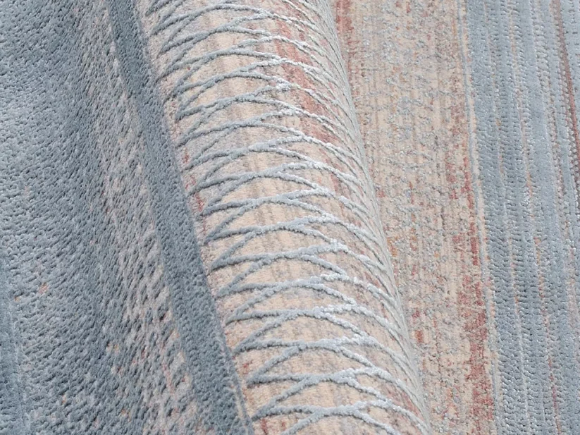 Koberec mení farbu podľa toho ako je otočený, motív je vyrobený z ligotavého prírodného materiálu, vďaka čomu koberec krásne hrá farbami.