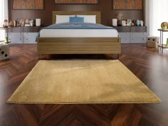 Zlato žltý jednofarebný koberec perfektne doplní tvoju hnedú spálňu.