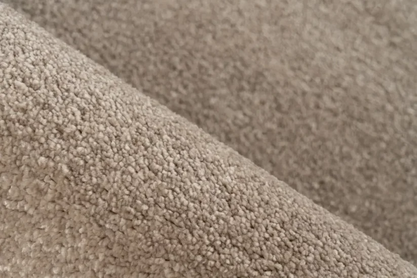 Jednofarebný béžový koberec má plný a hustý vlas, ktorý je príjemný na dotyk.