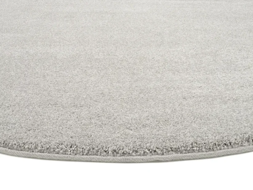Šedý kruhový koberec je elegantne obšitý vo farbe koberca.