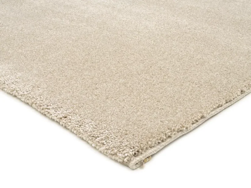 Béžový štvorcový koberec má dve strany prehnuté, čiže ukončenie je nenápadné. Dve strany má elegantne obšité v béžovej farbe koberca.